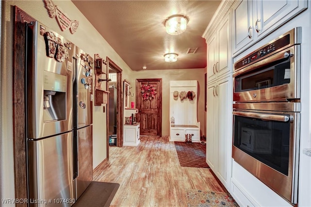 kitchen with appliances with stainless steel finishes and light hardwood / wood-style floors