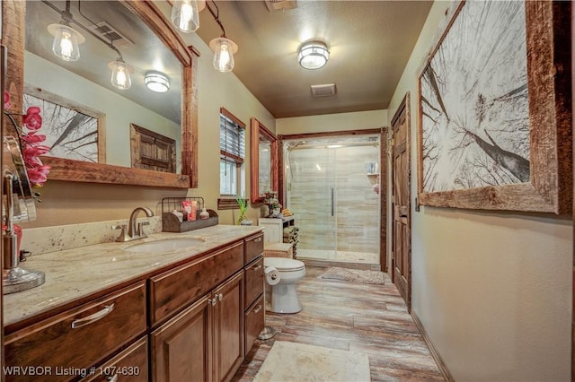 bathroom featuring a shower with door, vanity, and toilet