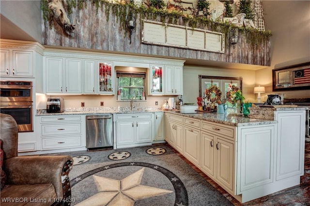 kitchen featuring light stone counters, sink, kitchen peninsula, and stainless steel appliances