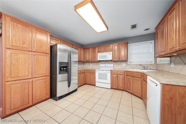 kitchen with white appliances, light countertops, a sink, and decorative backsplash