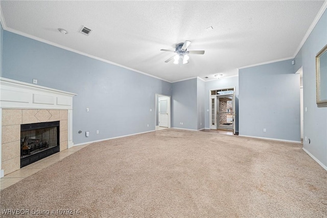 unfurnished living room with visible vents, a ceiling fan, a tile fireplace, carpet, and a textured ceiling