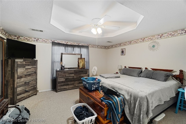 carpeted bedroom featuring ceiling fan, a raised ceiling, and a textured ceiling