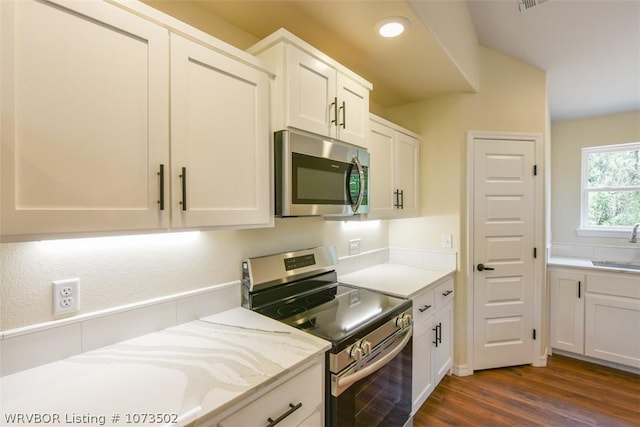 kitchen with dark wood-type flooring, white cabinets, stainless steel appliances, and sink