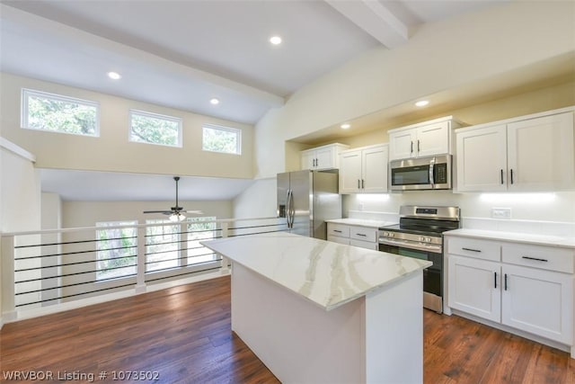 kitchen with beam ceiling, a center island, stainless steel appliances, and white cabinetry