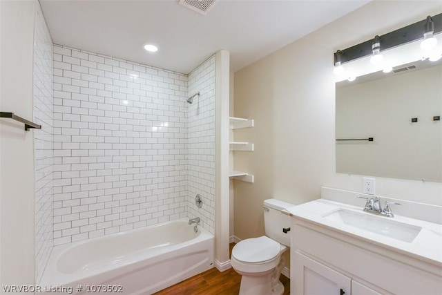 full bathroom featuring hardwood / wood-style floors, vanity, toilet, and tiled shower / bath