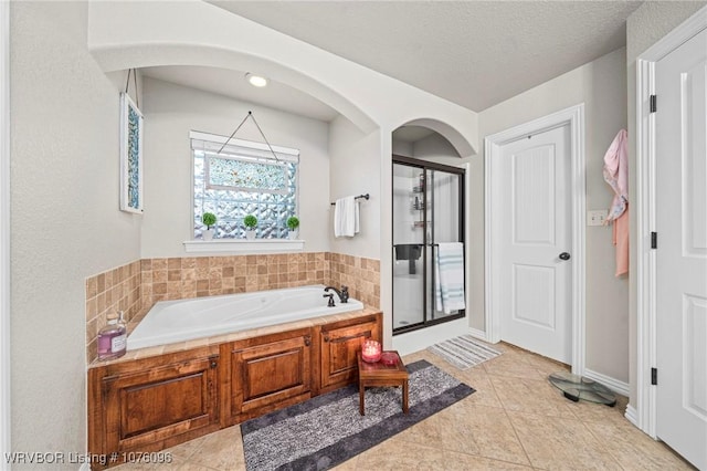 bathroom featuring separate shower and tub, tile patterned flooring, and a textured ceiling