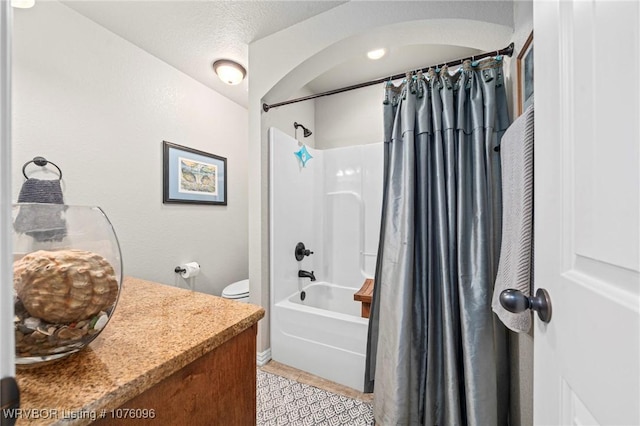 full bathroom with vanity, tile patterned flooring, toilet, shower / bath combo with shower curtain, and a textured ceiling