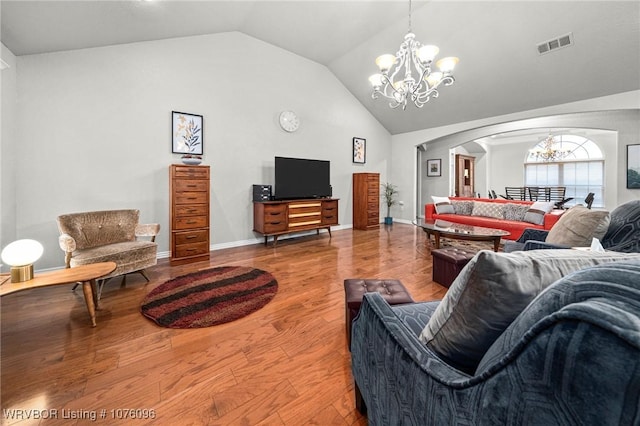 living room featuring hardwood / wood-style flooring, vaulted ceiling, and an inviting chandelier