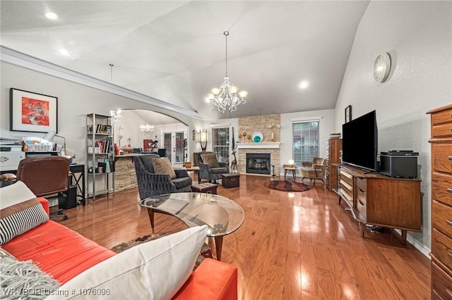 living room with a fireplace, wood-type flooring, vaulted ceiling, and a notable chandelier