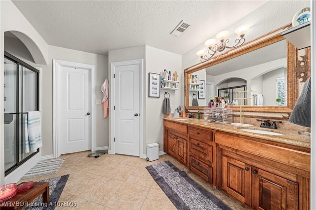 bathroom with tile patterned floors, vanity, and a textured ceiling