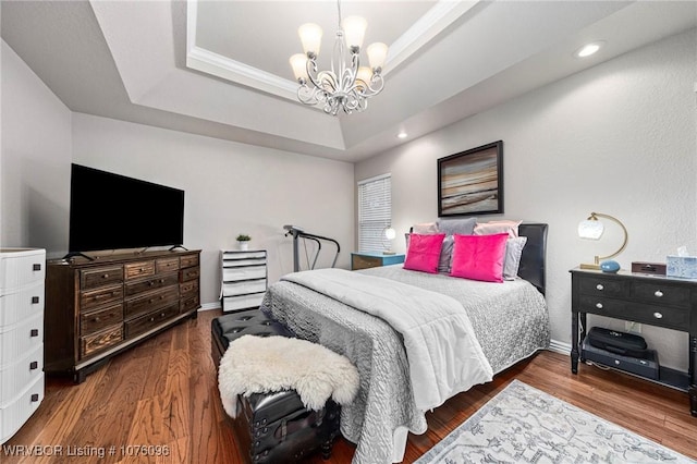 bedroom featuring a tray ceiling, an inviting chandelier, and hardwood / wood-style flooring