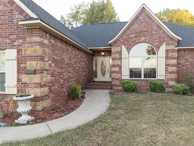 view of exterior entry featuring a lawn