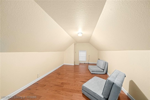 sitting room featuring hardwood / wood-style floors, lofted ceiling, and a textured ceiling