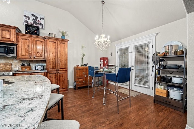 interior space with backsplash, light stone counters, vaulted ceiling, a chandelier, and hanging light fixtures