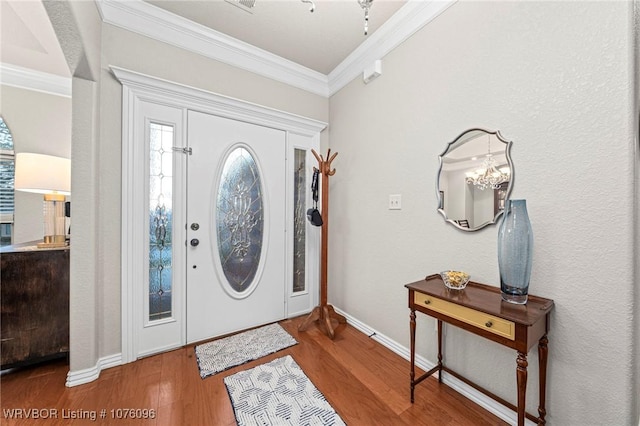 entrance foyer featuring hardwood / wood-style floors, an inviting chandelier, and ornamental molding