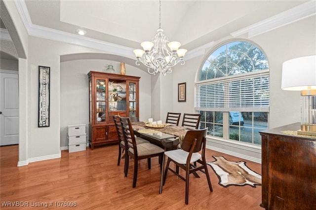 dining space with light hardwood / wood-style floors, ornamental molding, and an inviting chandelier