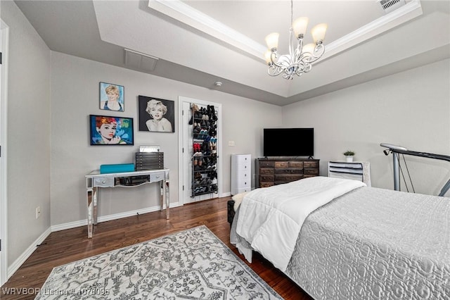 bedroom featuring an inviting chandelier, dark hardwood / wood-style flooring, a closet, and a tray ceiling