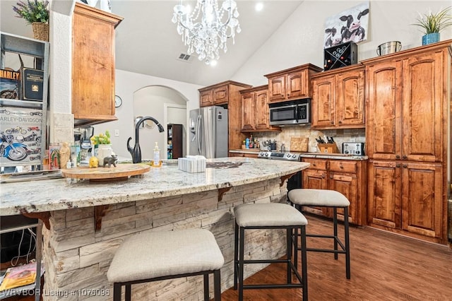 kitchen featuring decorative backsplash, dark hardwood / wood-style floors, light stone countertops, and appliances with stainless steel finishes