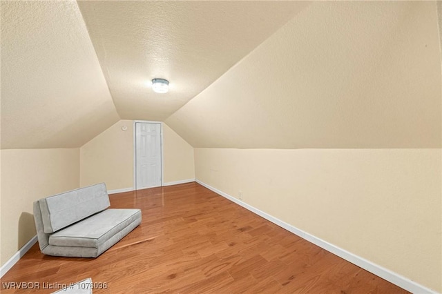 bonus room with vaulted ceiling, wood-type flooring, and a textured ceiling