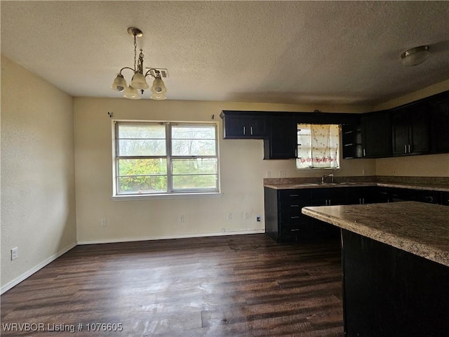 kitchen with sink, hanging light fixtures, an inviting chandelier, dark hardwood / wood-style flooring, and a textured ceiling