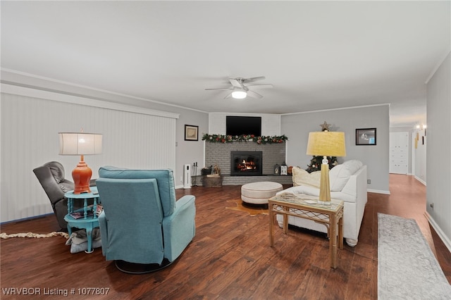 living room with ceiling fan, dark hardwood / wood-style flooring, ornamental molding, and a fireplace