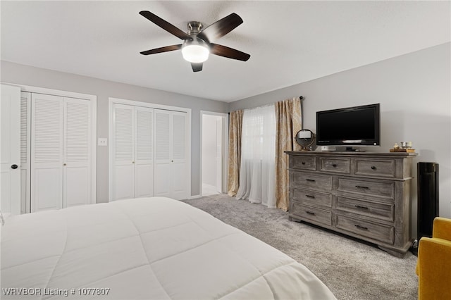 carpeted bedroom featuring ceiling fan and two closets