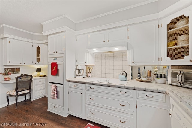 kitchen featuring white appliances, dark wood-type flooring, decorative backsplash, tile counters, and white cabinetry