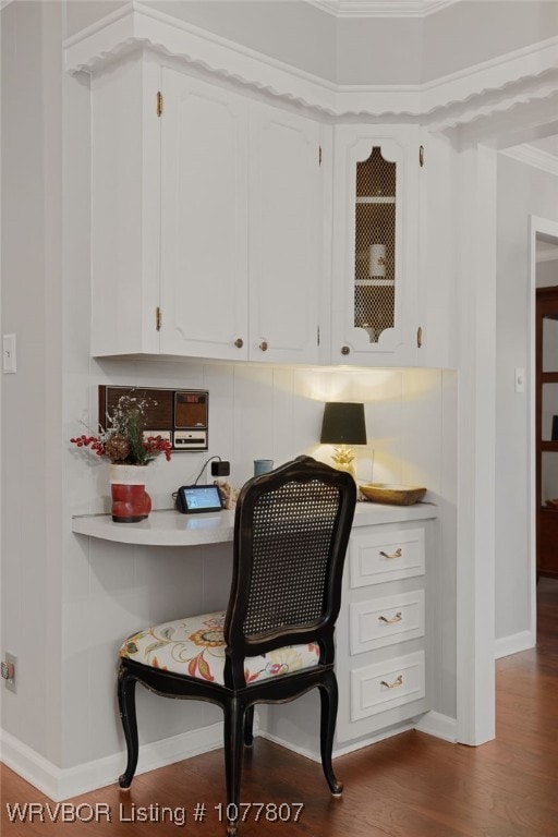 home office with hardwood / wood-style floors, built in desk, and crown molding