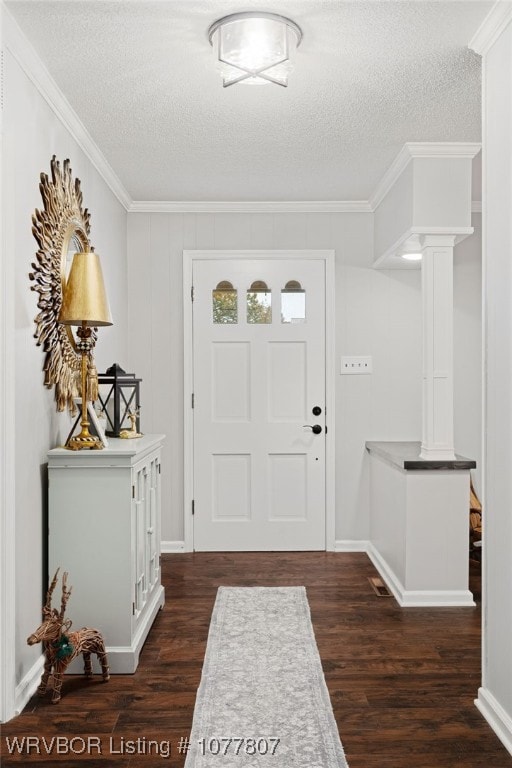 entryway featuring ornamental molding, a textured ceiling, decorative columns, and dark wood-type flooring