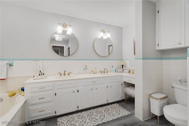 bathroom with vanity, toilet, tile walls, and a tub