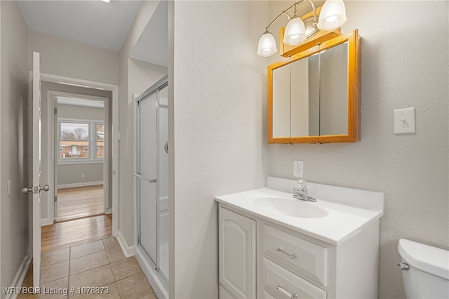 bathroom featuring vanity, toilet, an enclosed shower, and tile patterned flooring