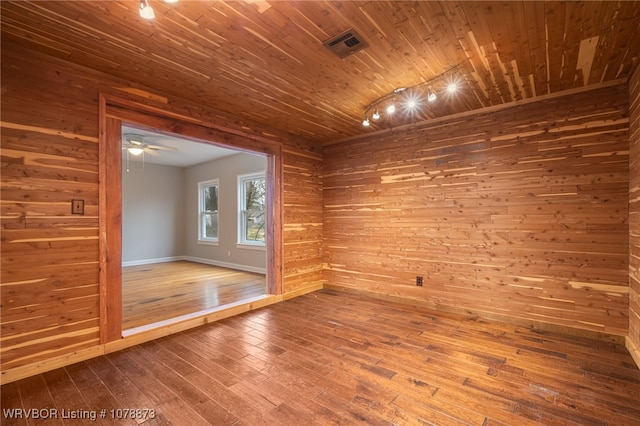 empty room featuring ceiling fan, wooden walls, hardwood / wood-style floors, and wooden ceiling