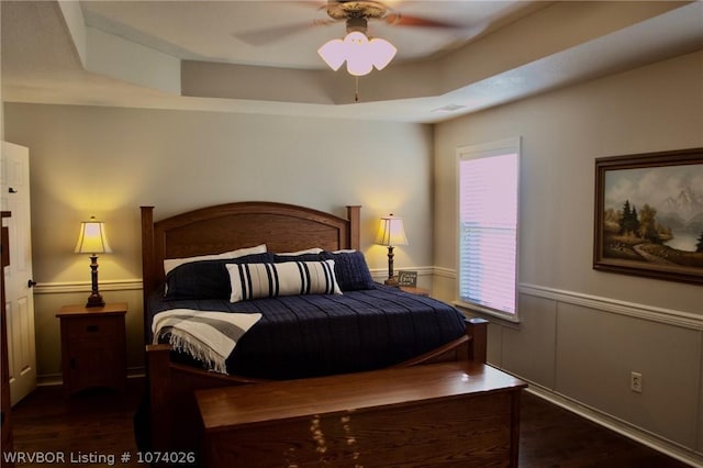 bedroom with dark hardwood / wood-style flooring, a raised ceiling, and ceiling fan