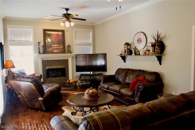 living room featuring ceiling fan, a fireplace, wood-type flooring, and ornamental molding