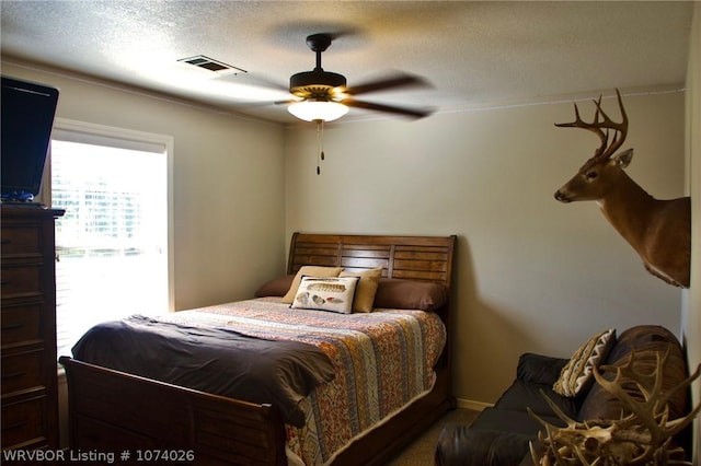 bedroom with ceiling fan and a textured ceiling