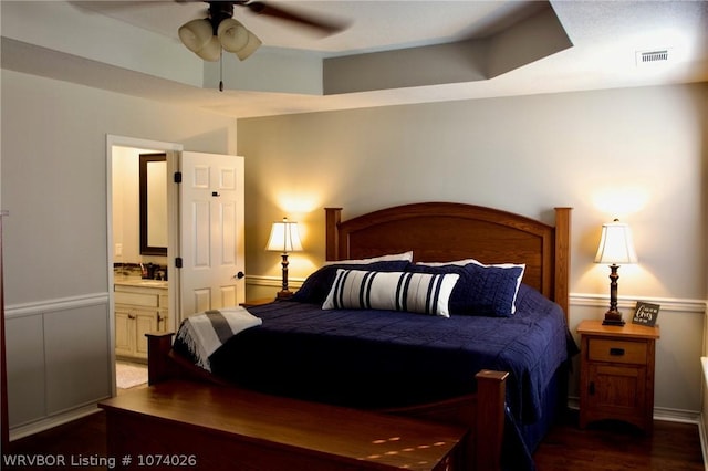 bedroom with ceiling fan, dark wood-type flooring, and ensuite bath