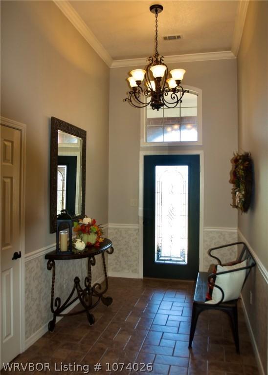 entrance foyer with an inviting chandelier and ornamental molding