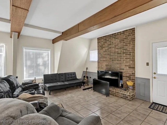 living room with beamed ceiling, light tile patterned flooring, and a brick fireplace