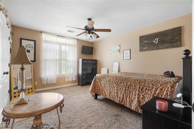 bedroom with ceiling fan, light carpet, and a textured ceiling