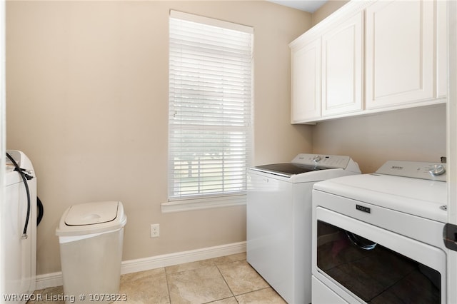 laundry area with cabinets, light tile patterned flooring, and washing machine and dryer