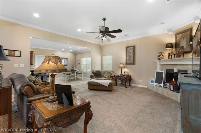 carpeted living room featuring a tile fireplace, ceiling fan, and ornamental molding