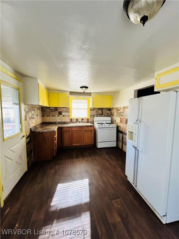 kitchen featuring white appliances, dark hardwood / wood-style floors, sink, and backsplash