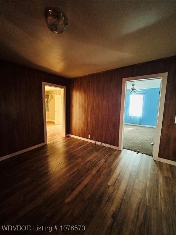 empty room with dark wood-type flooring and wooden walls