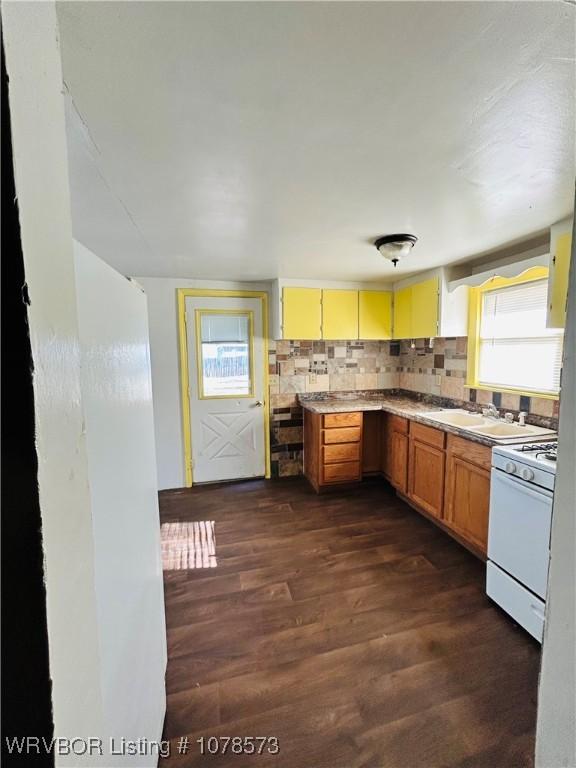 kitchen featuring a wealth of natural light, white gas stove, backsplash, and dark hardwood / wood-style flooring