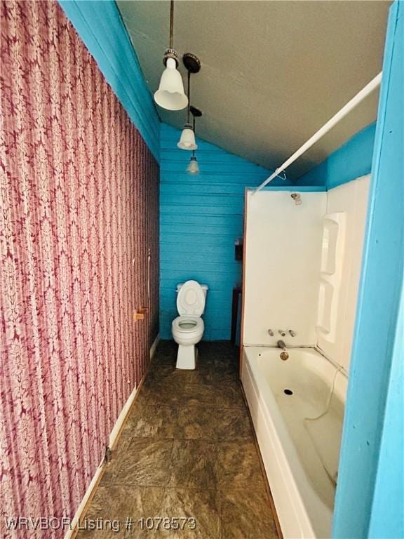 bathroom featuring lofted ceiling, toilet, and bathing tub / shower combination