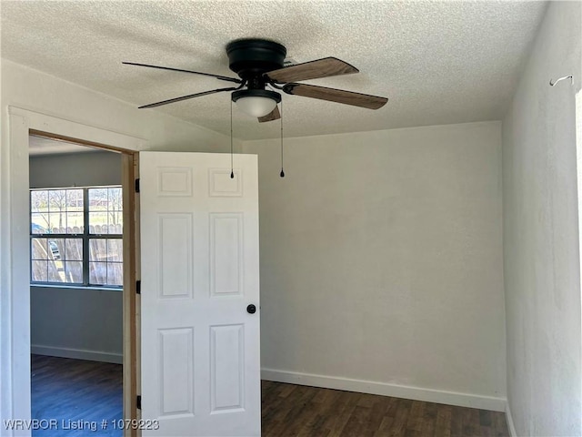 unfurnished room featuring a textured ceiling, dark wood-style flooring, a ceiling fan, and baseboards