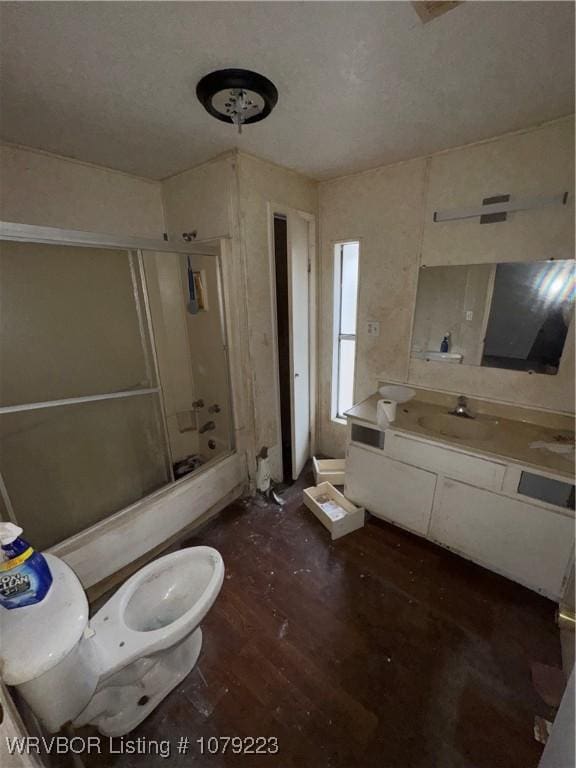 bathroom featuring enclosed tub / shower combo, vanity, toilet, and wood finished floors