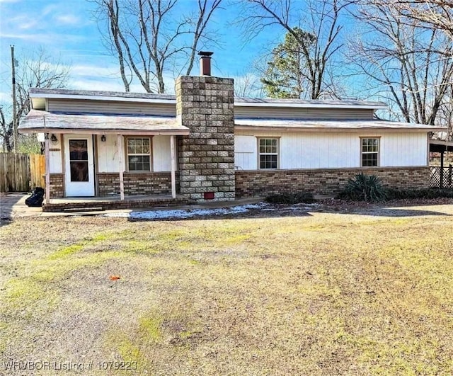 view of front of house featuring a porch, brick siding, fence, and a chimney