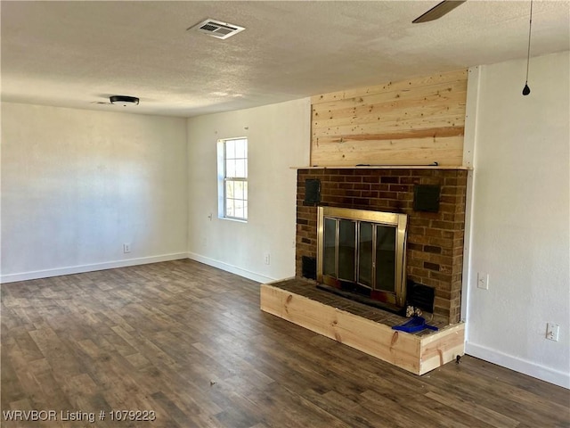 unfurnished living room featuring visible vents, a fireplace, a textured ceiling, and wood finished floors