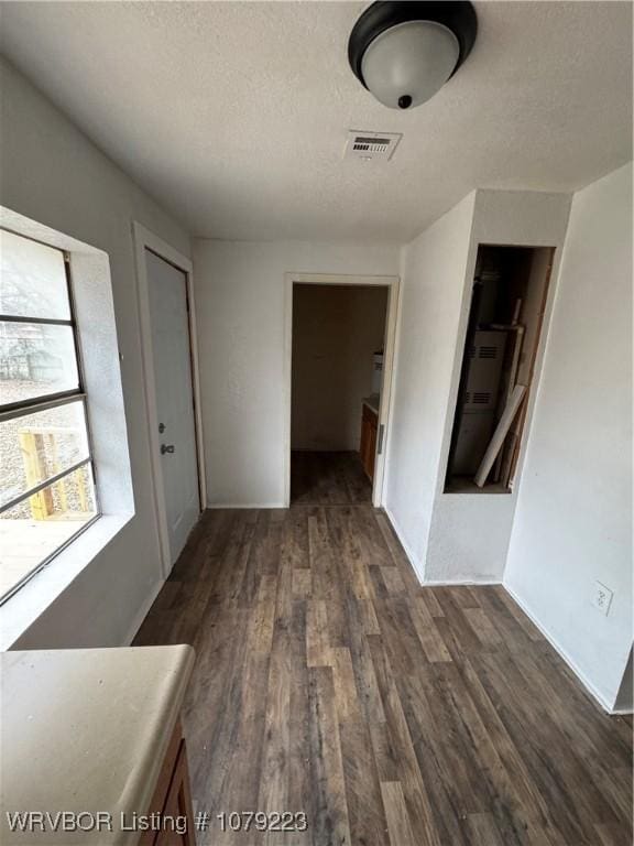 hall featuring a textured ceiling, visible vents, and dark wood-type flooring